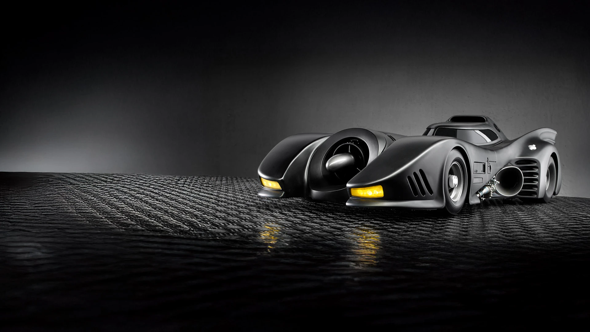 Image of the 1989 Batmobile on concrete with dark background.