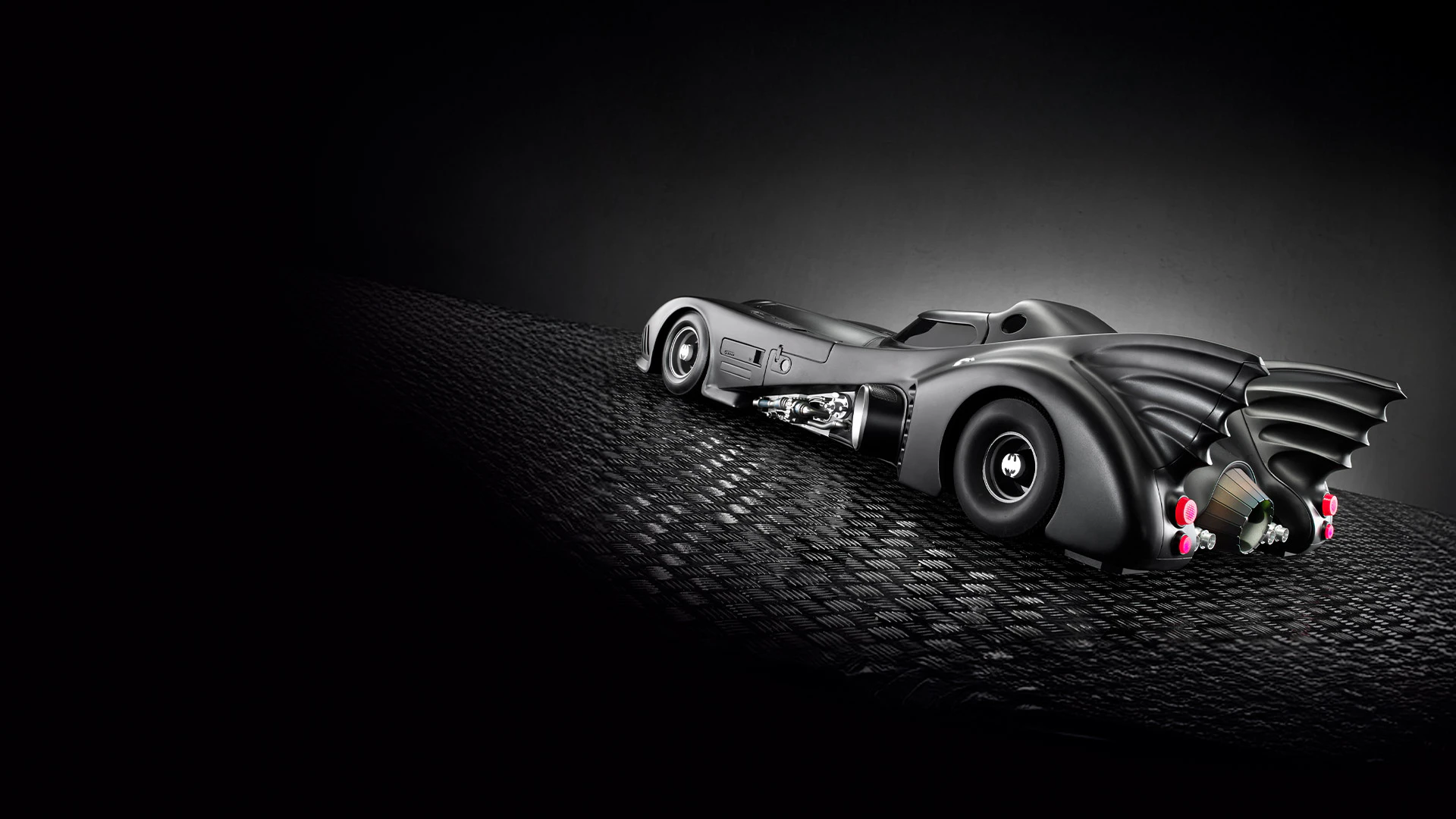 Obrázok Batmobilu z roku 1989 na betóne s tmavým pozadím.